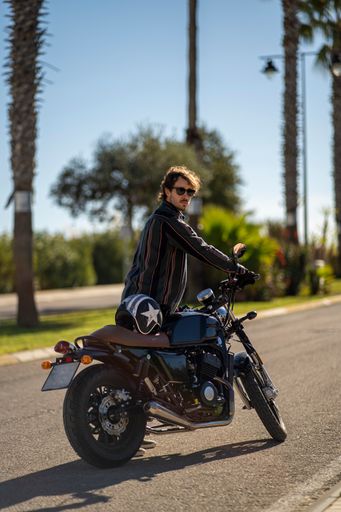 A closeup of a man with a motorcycle posing in stylish clothes
