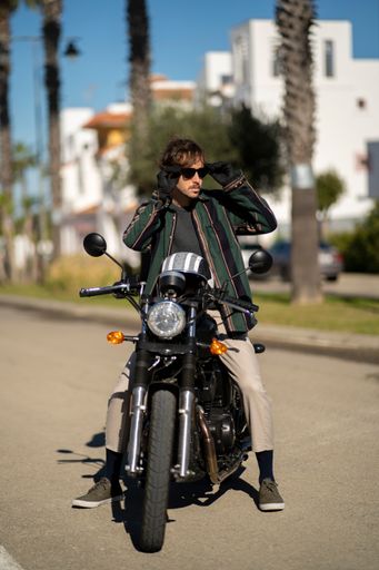 A closeup of a man with a motorcycle posing in stylish clothes