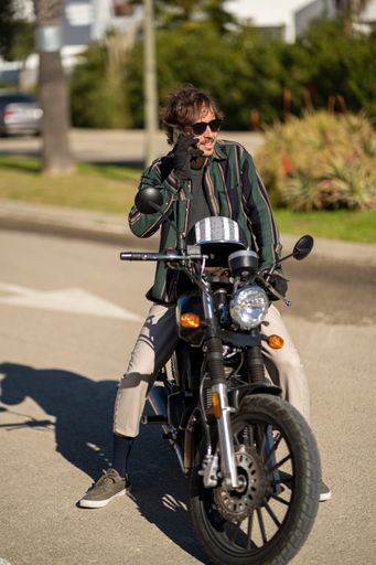 A closeup of a man with a motorcycle posing in stylish clothes