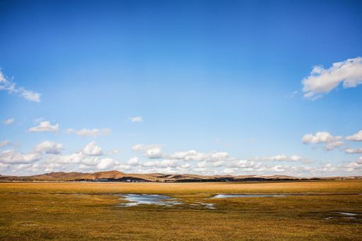 A wet ground in a field against a cloudy sky