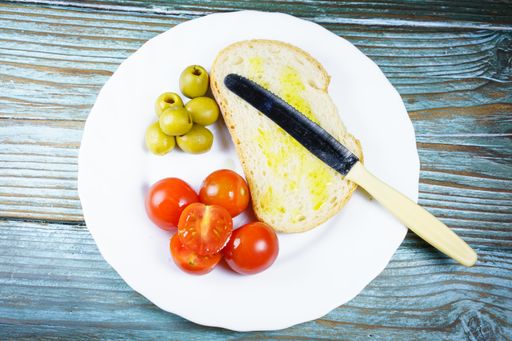 A top view of a plate with bread, olives and potatoes in a plate