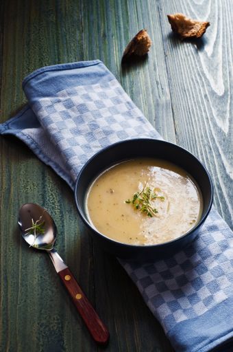 A vertical shot of a bowl of soup seasoned with spices on a wooden table