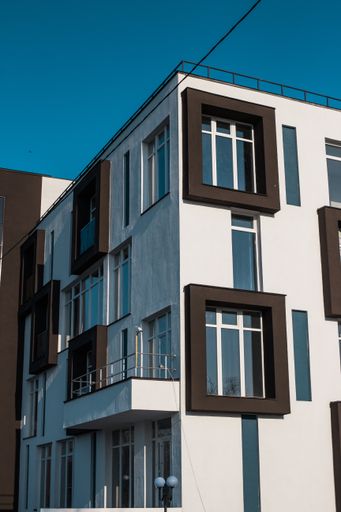 A low angle shot of a tall white and brown apartment building