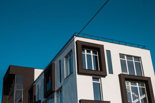 A low angle shot of a tall white and brown apartment building