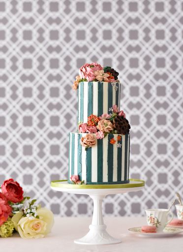 A two-tiered delicious cake with the decoration of colorful flowers on a white stand
