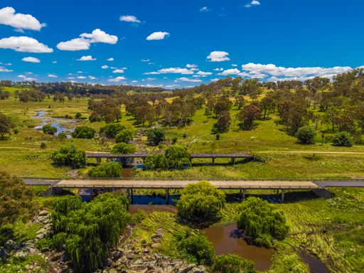 An aerial view of green lands, trees, and the Mann River near Glen Innes, Australia