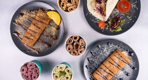 A top view of sweet crepes and tortilla in gray plates and ice cream in different flavors on a white table