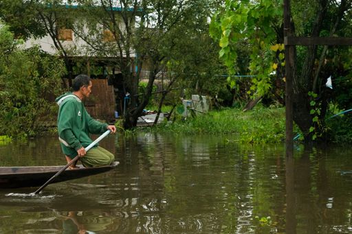 Burmese man rowing a long boat used for transportation in Inle Lake, on a cloudy day during monsoon season. Shan Region, Myanmar, Burma, SE Asia.