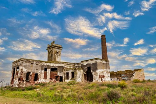 The ruined building of slaughterhouse Matadero in Villa Epecuen village against a blue cloudy sky