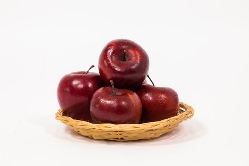 A ripe red apples in wicker basket on white background.