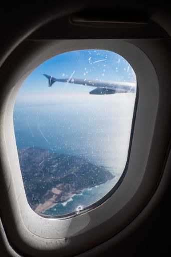 A vertical shot through the window of an airplane on an island.