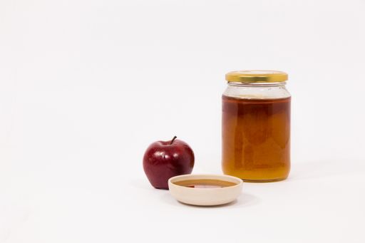 The red apple and jar of honey bowl of honey are isolated on a white background. Symbols of Jewish New Year - Rosh Hashanah.
