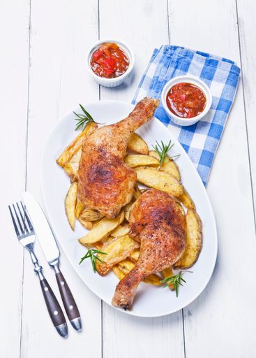 A closeup shot of grilled chicken meal with sauces and fried potatos