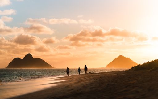 A silhouette photo of people and mountains in Lanikai Beach Oahu Hawaii at sunset