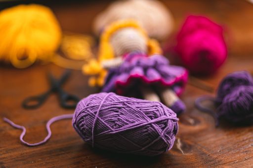 A product photo of a handmade crochet toy doll for kids with its tools and materials