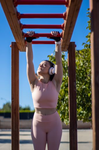 A female exercising while hanging from one bar to another in an outdoor gym
