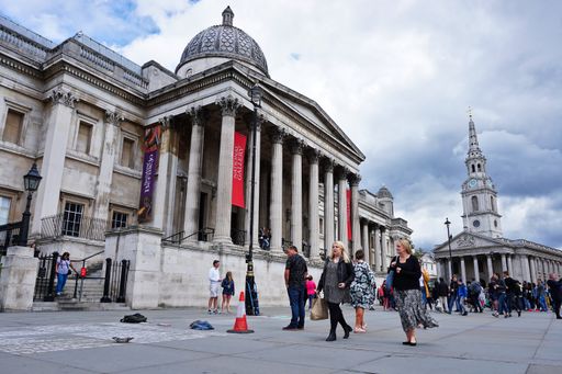 A view of tourists walking in front of the National Gallery, art museum in Trafalgar Square, Westminster, Central London, England.