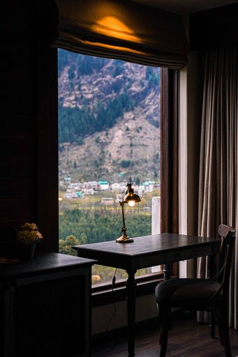 A vertical shot of a lamp on a study table with a beautiful mountain view in the background