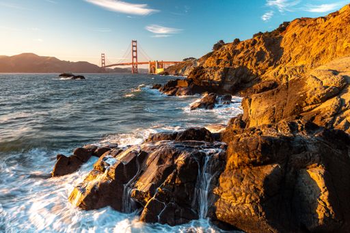 A beautiful shot of the Golden Gate Bridge near a rocky sunny shore