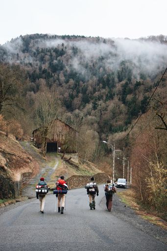 A vertical shot of tourists walking and a mountain covered with fog