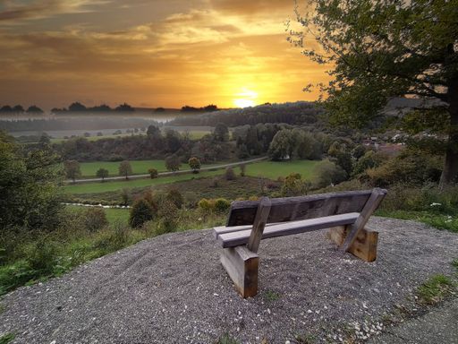A bench on a hill in a rural park at sunset or sunrise
