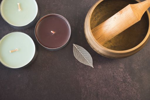 A top view of a Tibetan singing bowl and aromatic candles on dark background