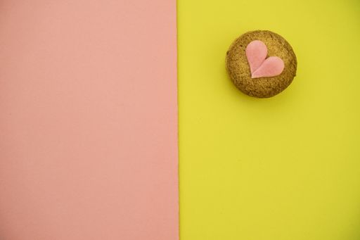 A top view of a cookie decorated with a pink heart on a colorful background