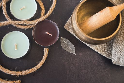 A top view of a Tibetan singing bowl and aromatic candles on dark background