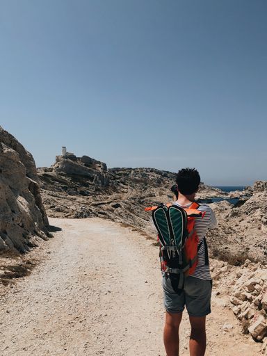 A vertical shot of a man with a backpack and flippers taking photos