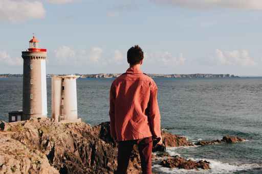 A man standing near the lighthouse during daytime