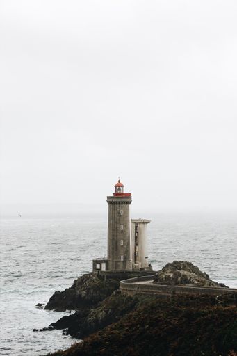 A lighthouse with a red top and the beautiful sky