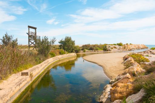 A scenic view of a river flowing through rocky fields with greenery near the watch out tower