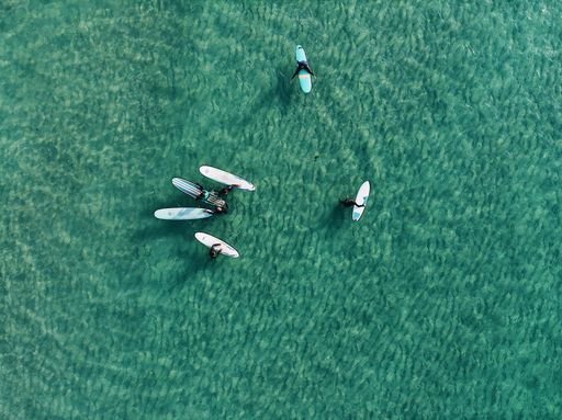 The top view of the swimmers with surfing boards in the clear water