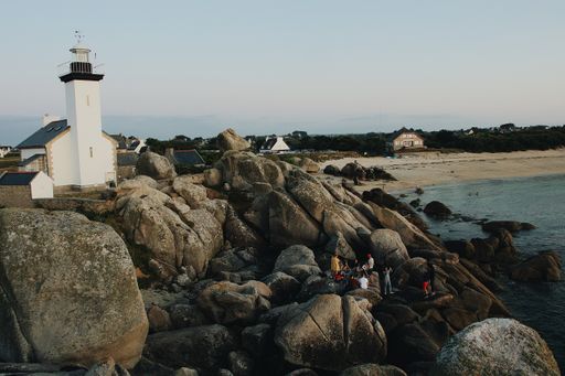 The tourists near the lighthouse on the rocky shore of the sea