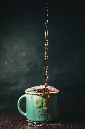 A vertical shot of an overfilled cup of coffee