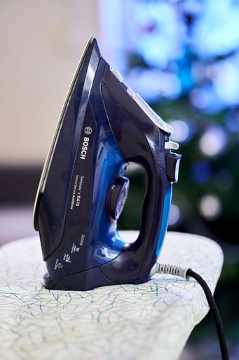 A vertical shot of the Bosch brand iron on a board in a room.