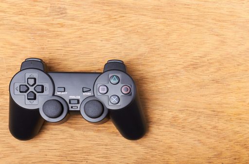 A Sony Computer Entertainment PlayStation 2 video game controller on a wooden table