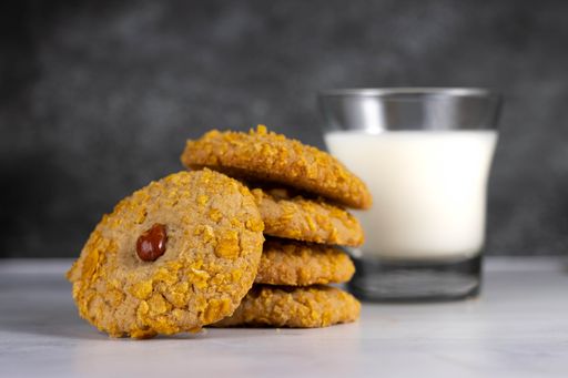 A close-up shot of a pile of cookies in the background of a cup of milk.