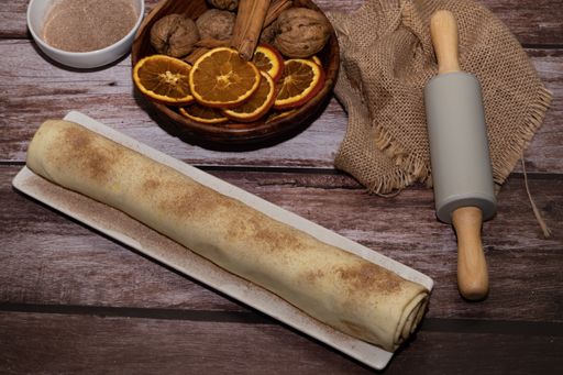 whole cinnamon and sugar roll ready to cut and bake on a white baking tray