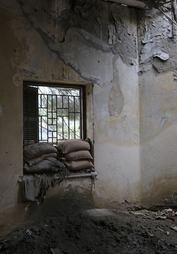 A vertical shot of an abandoned building with old cushions on the window sill