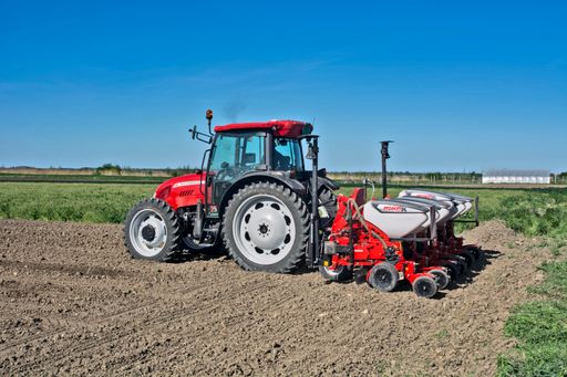 A closeup of a farmer with a tractor sows corn on his field