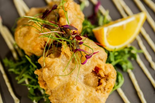 A closeup shot of crispy fried chicken with lemon and vegetables