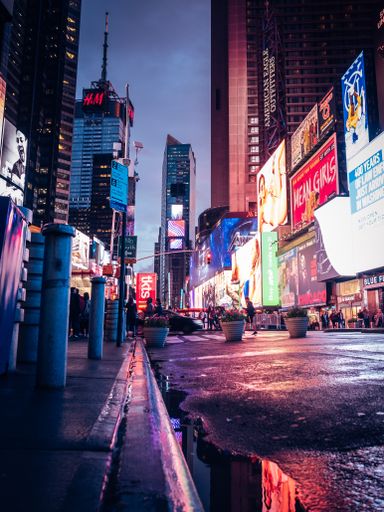 A vertical shot of the nightlife in New York City - Time Square with billboards and tourists