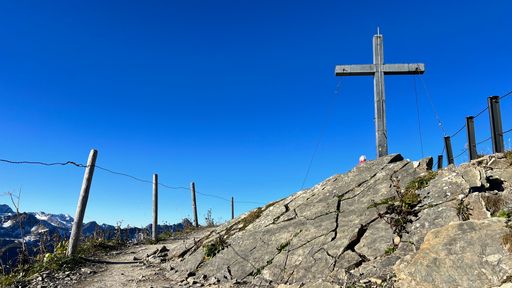 A view of a cross erected on a rocky ground against a cloudless blue sky
