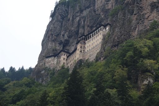 A low angle shot of the Sumela monastery, Trabzon on the mountain with trees against a light sky