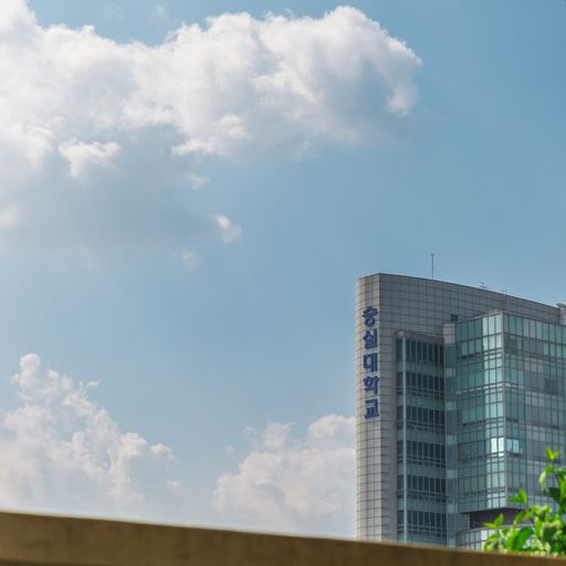 A low angle shot of a modern glass building under the clouds in the blue sky in Seoul, South Korea