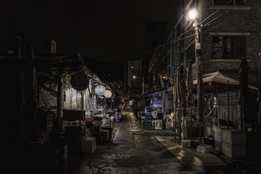 A street market on a dark alley surrounded by stores and shops captured in Seoul, South Korea