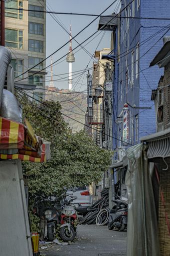 A vertical shot of N Seoul Tower visible thought the buildings and houses in Seoul, South Korea