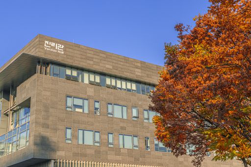 A low angle shot of a stone building behind an autumnal tree under the clear blue sky in Seoul, South Korea