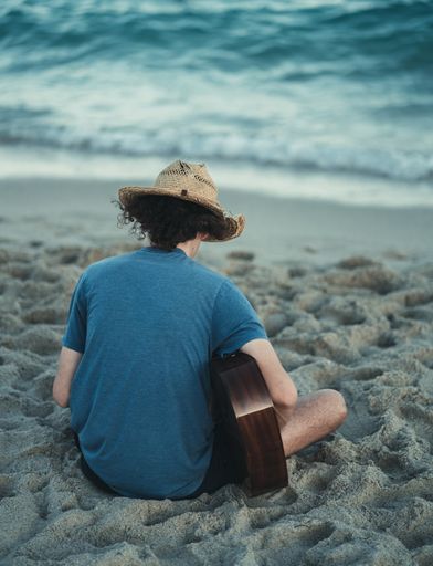 A back view of a man playing guitar on a beach